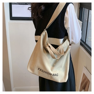 Detail of a large beige canvas tote bag with black Fashion Bag print and long strap