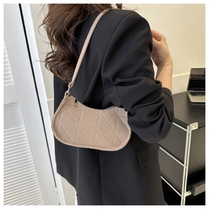 Detail of beige quilted hobo bag showing diamond stitching and adjustable strap on a shoulder