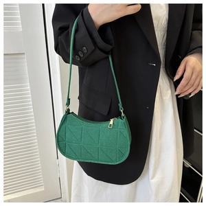 Detail of green geometric quilted shoulder bag worn with a black blazer and white dress