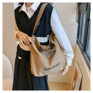 Detail showing brown canvas tote bag with FASHION BAG text and adjustable strap on a model