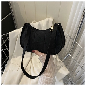 Detail of black quilted half-moon shoulder bag with geometric stitching and gold zipper