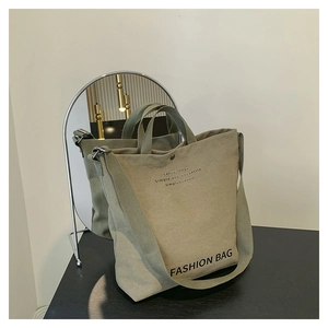 Close-up of army green canvas bag with wide shoulder strap and magnetic closure detail
