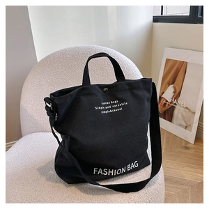 Detail of black canvas tote showing fashion print, metal buckle and adjustable strap