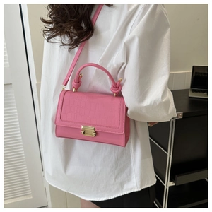 Detail of pink faux crocodile leather bag featuring a gold square lock and knotted handle
