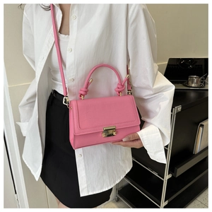 Detailed view of pink crocodile pattern crossbody bag worn by a model in a studio