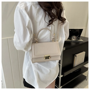 Fashionable beige crossbody bag with crocodile pattern and knot handle detail worn by model
