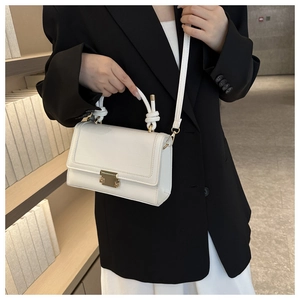 Detail of white crocodile pattern handbag with unique nautical knot woven handle and gold lock