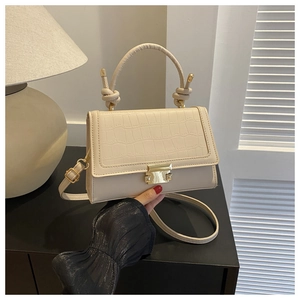 Detail of cream PU leather crossbody bag with faux crocodile texture and gold metal clasp