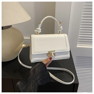 Detail of white crocodile embossed mini bag with gold buckle and knot handle