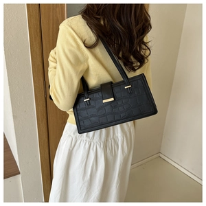 Close-up of black crocodile embossed leather shoulder bag with gold hardware detail
