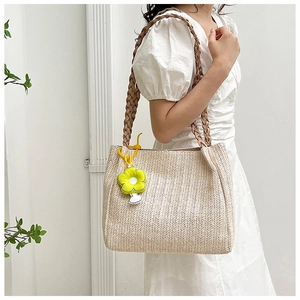 Detail of straw shoulder bag with V-weave texture and lime green flower pendant
