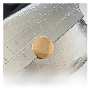 Close-up of gold metal buckle on silver crocodile texture handbag with metallic finish