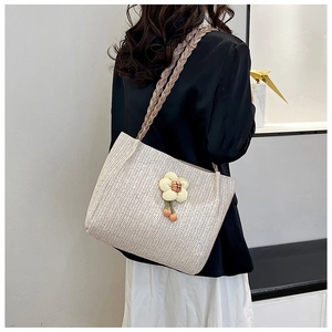 Detail view of cream woven tote bag with 3D flower charm and braided shoulder strap
