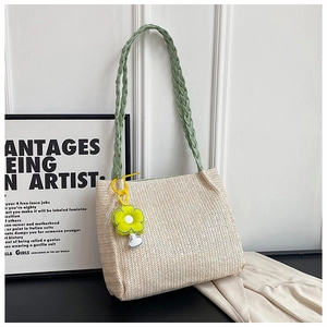 Detail of straw woven tote bag with green handles and daisy floral bag charm decoration