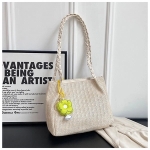 Detail of cream woven tote bag with wavy texture and green sunflower pendant