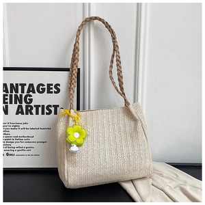 Detailed herringbone texture of beige woven tote bag with floral daisy charm accessory