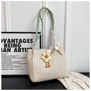 Detail of cream woven tote bag with green handles and yellow floral accent