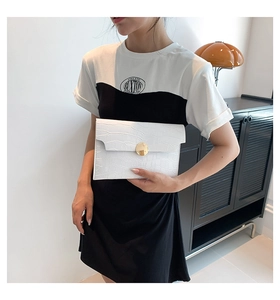 Detail of white crocodile embossed envelope clutch with a gold round metal buckle