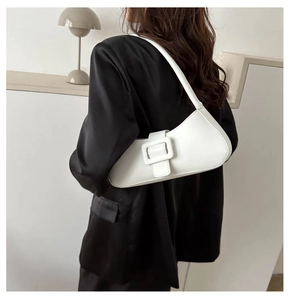 Minimalist white leather baguette bag with a square buckle shown on a model