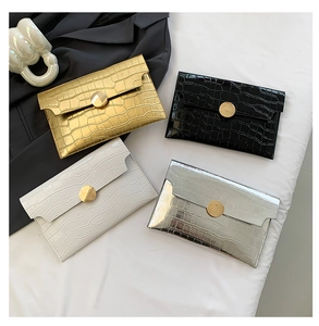 Vista piatta di pochette a busta con trama a coccodrillo in oro, nero, bianco e argento