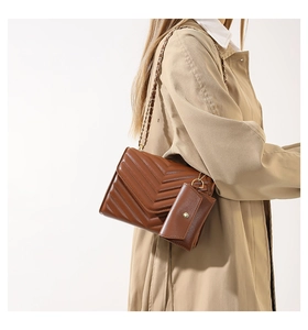 Details der braunen Stepptasche mit Goldkette und Mini-Beutel an einem Model getragen