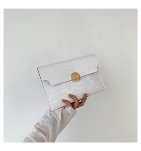 Dettaglio della pochette bianca motivo coccodrillo con una grande fibbia in metallo oro