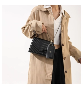 Detail einer schwarzen Steppleder-Umhängetasche mit Kettenriemen und Mini-Tasche am Model