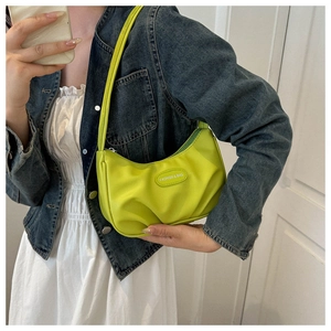 Detail view of neon green pleated shoulder bag worn with casual denim jacket outfit