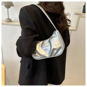 Detail of silver pleated shoulder bag with metallic texture shown on a black blazer