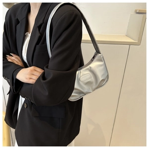 Detailed view of silver pleated shoulder bag with fashion label on black blazer