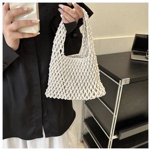 Detail of a minimalist cream-white woven tote bag featuring a bohemian hollow-out mesh design