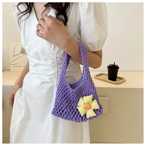Close-up of a purple hand-woven crochet handbag featuring a yellow and white floral charm