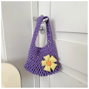 Detail of purple knitted mesh handbag featuring a woven sunflower on a white door