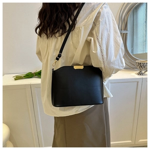 Detail of black faux leather crossbody bag with adjustable strap and gold metal buckle