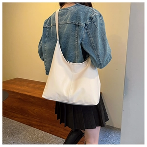 Detailed view of white leather tote bag with vertical stitching and wide shoulder strap