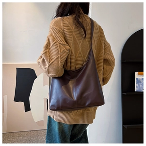 Side view of model wearing a large brown leather tote bag with vertical stitching