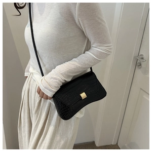 Close-up of black crocodile-pattern crossbody bag featuring elegant gold metal buckle
