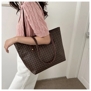 Detail of a brown tote bag with vintage geometric pattern worn on a pink knit top