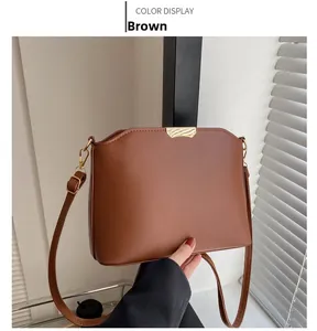Detail of a brown matte faux leather shoulder bag featuring a square metal buckle and flap