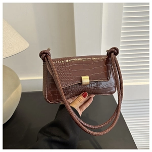 Detail of brown crocodile pattern shoulder bag with a polished golden metal buckle