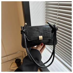 Detail of black crocodile texture handbag with golden rectangular metal lock closure