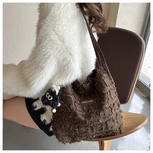 Détail du sac seau en jacquard marron avec franges et charmant pendentif en peluche