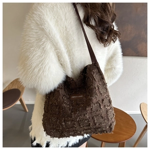 Détail du sac fourre-tout à carreaux marron avec texture frangée et bandoulière