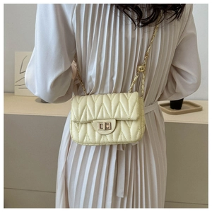 Detail of light yellow quilted leather crossbody bag with metal chain strap and turn-lock