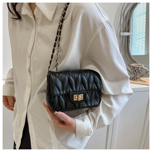 Close-up of a black quilted leather shoulder bag with a gold metal turn-lock and chain strap