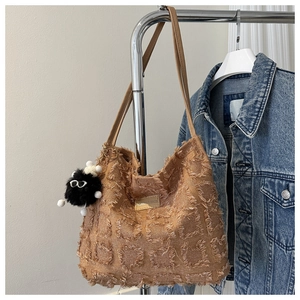 Détail d'un sac cabas en toile à damier avec des bords effilochés et un charm monstre noir