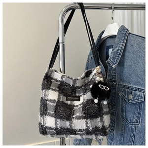 Gros plan sur un cabas en tweed à carreaux noir et blanc avec franges et breloque peluche