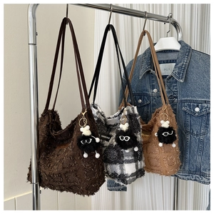 Détail de sacs fourre-tout à bords effilochés avec breloques monstre en peluche noire