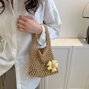 Chic beige woven hollow mini handbag with a yellow floral charm held by a model