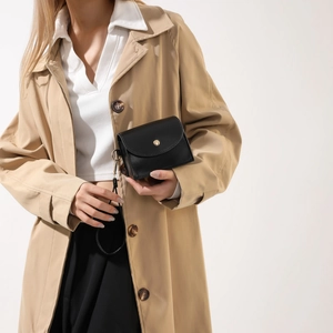 Schicke schwarze Umhängetasche mit goldener Rundschnalle von einem Model gezeigt